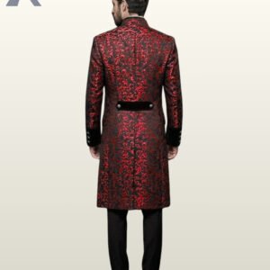 Full rear view of a model wearing a long crimson red brocade gothic frock coat highlighting a black velvet waist half-belt and centered split vent.