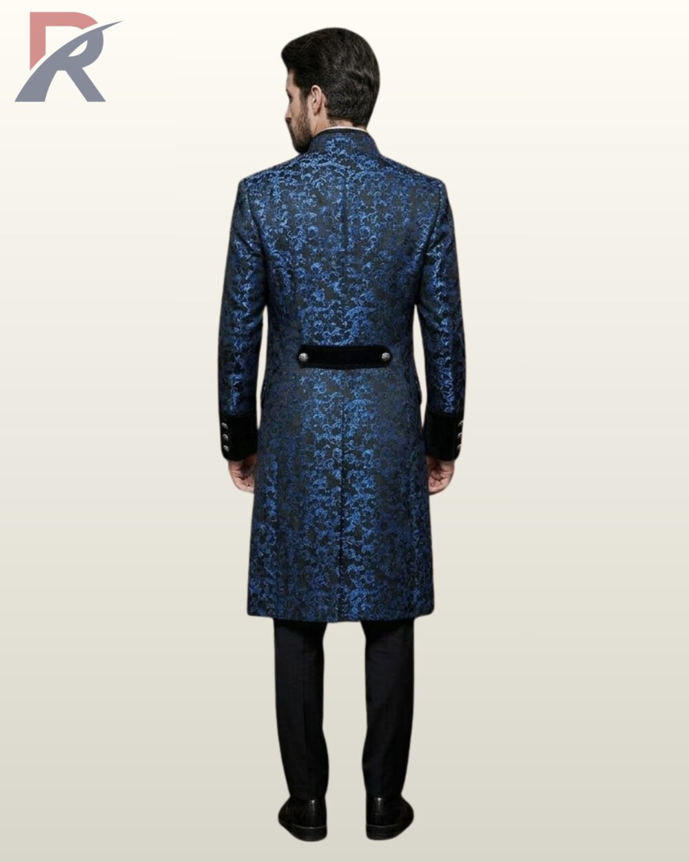 Back perspective of a men's blue floral brocade Victorian tailcoat showing velvet sleeve cuff bands, standing collar, and black dress pants.