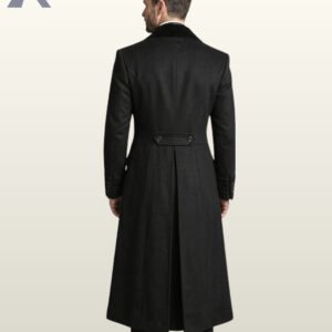 Full rear model view of a men's black wool Victorian frock coat showing a velvet upper collar, buttoned back half-belt waist, structured princess seams, and a long pleated split vent.