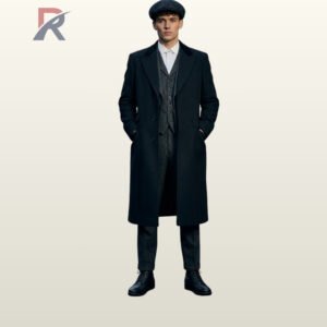 Men's vintage Peaky Blinders coat styled with dark velvet notch lapels, hands in coat pockets, collared shirt, and black lace-up boots.
