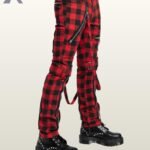 Three-quarter side profile view of a model wearing red buffalo plaid punk bondage pants displaying thigh buckled straps and silver zipper pockets.