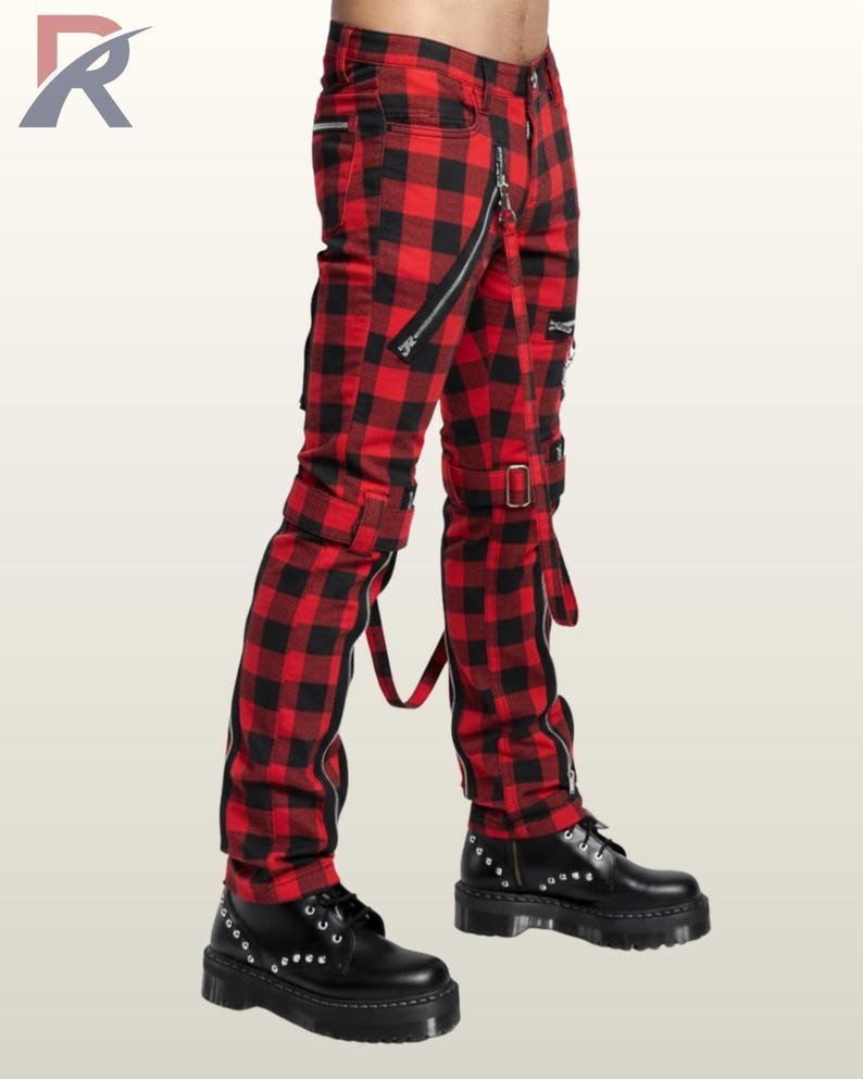 Three-quarter side profile view of a model wearing red buffalo plaid punk bondage pants displaying thigh buckled straps and silver zipper pockets.