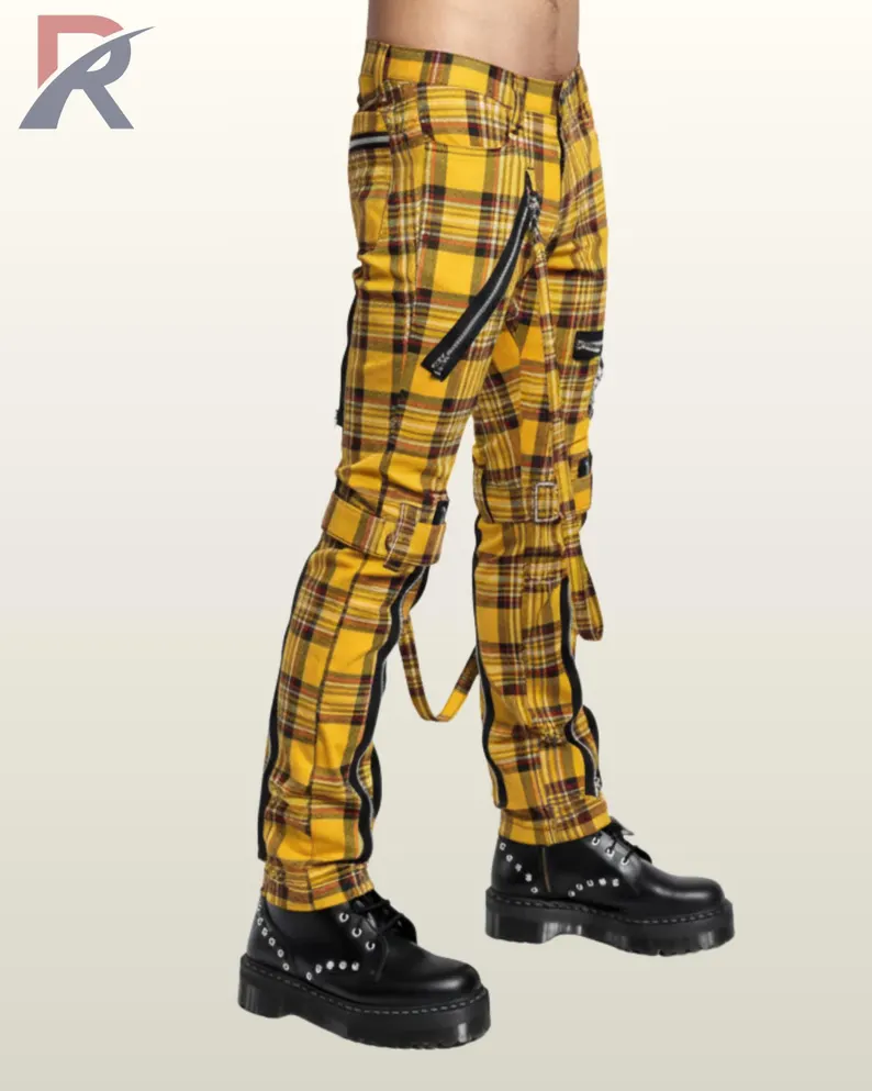 Three-quarter side profile view of a model wearing yellow tartan plaid punk bondage pants displaying thigh buckled straps and silver zipper pockets.