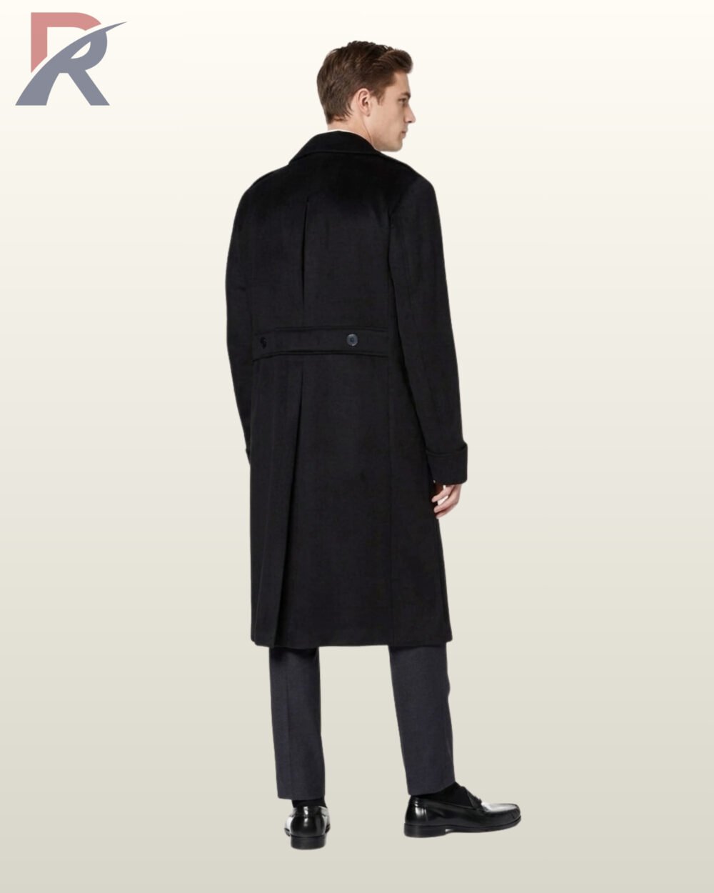 Full rear view of a model wearing a long black wool officer coat highlighting a buttoned rear half-belt waist, center pleat, and long back split vent.