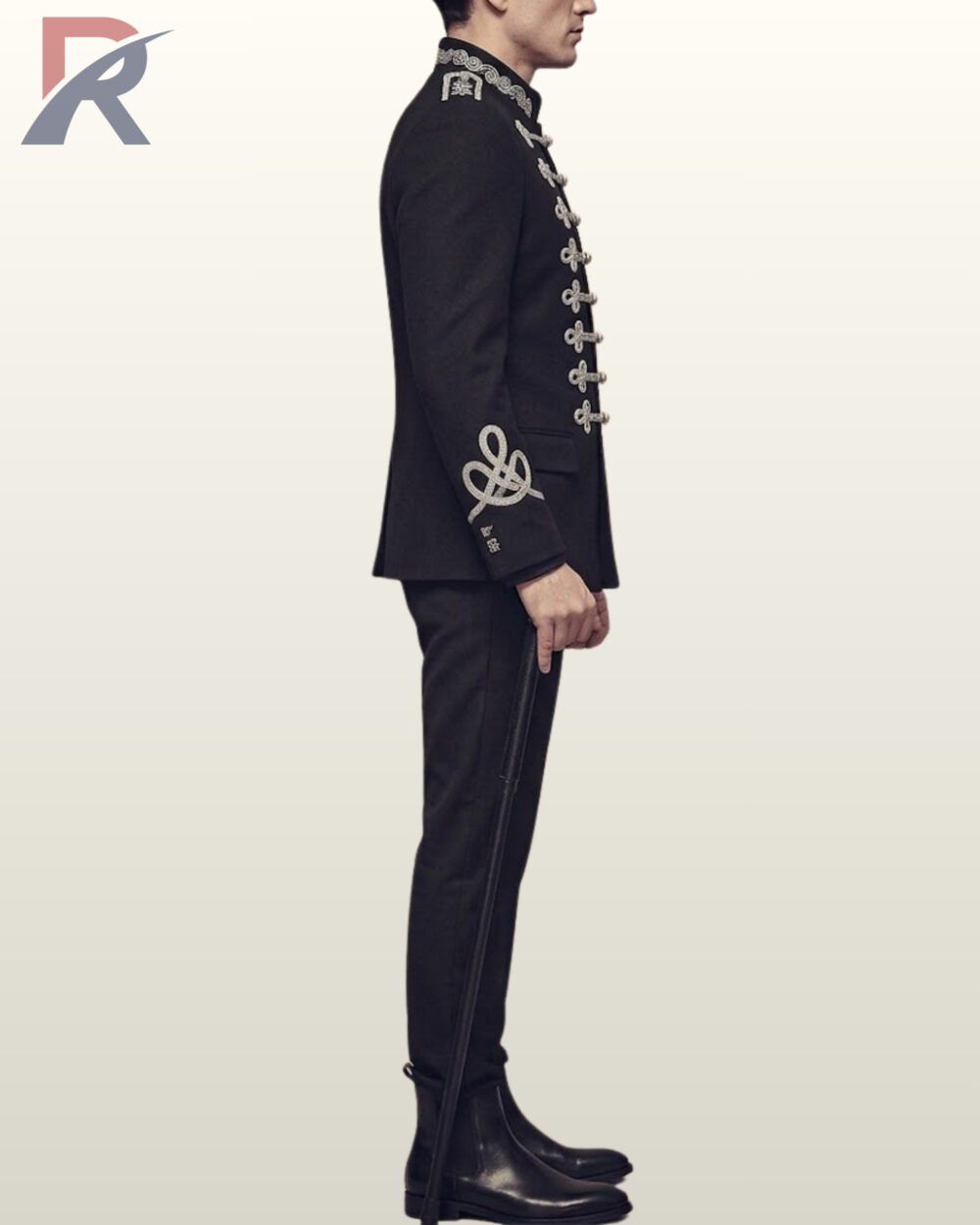 Full side profile view of a model wearing a men's black military hussar suit featuring silver braided sleeve knots, silver collar embroidery, and black riding boots.