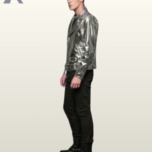 Side profile view of a model wearing a metallic silver patent leather biker jacket detailing sleeve zips, lapel snaps, and waist belt hardware.