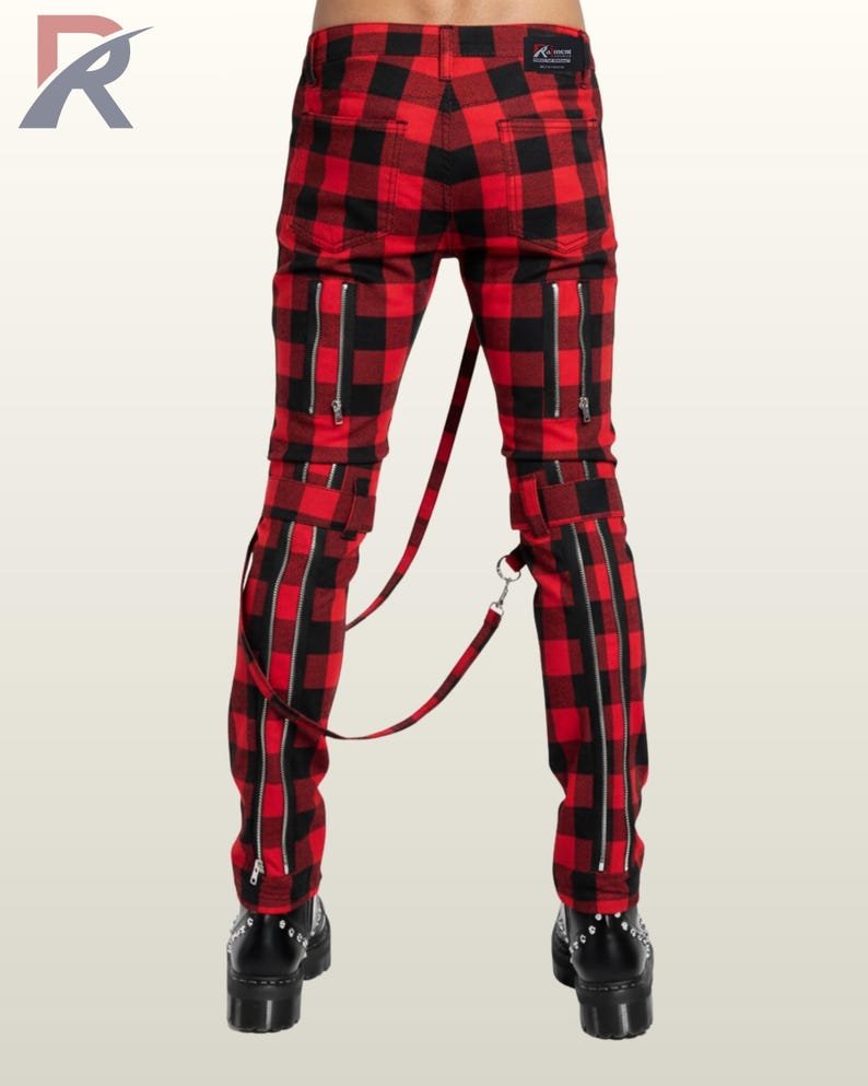 Full rear view of a male model wearing red buffalo plaid punk bondage pants showing zippered back pockets and connected leg straps.