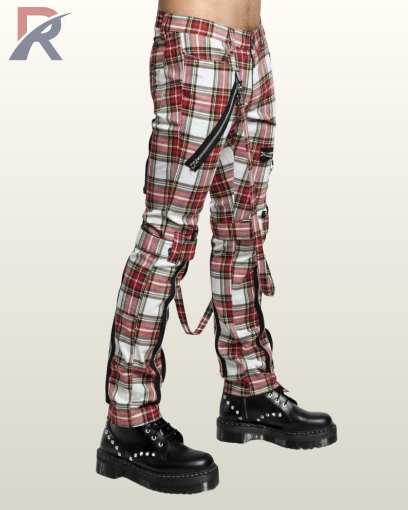 Side perspective of men's white and red checkered gothic bondage trousers highlighting outer leg zippers, hanging strap details, and studded combat boots.