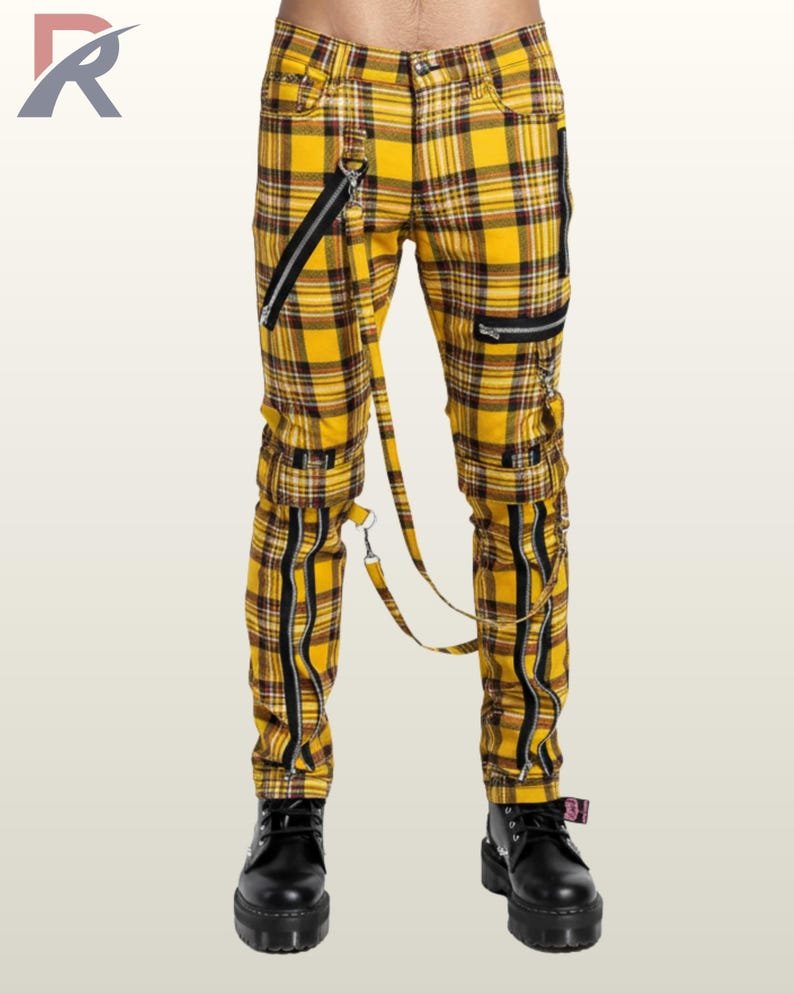 Full front view of a male model wearing yellow tartan plaid punk bondage pants with silver zippers, thigh straps, and hanging D-ring bondage straps.