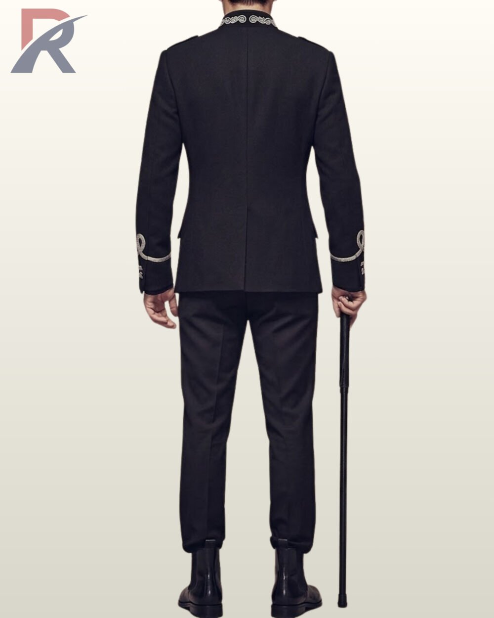 Full rear view of a model wearing a tailored black military hussar suit with silver collar embroidery, back vent split, and silver cuff loops, holding a black cane.