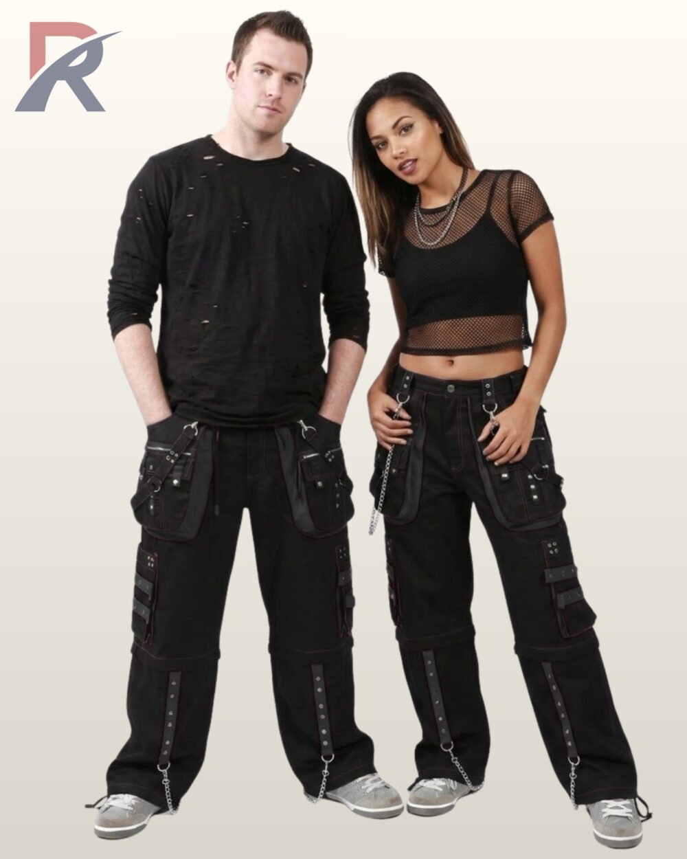 Front perspective of a man and woman modeling all-black industrial goth trousers detailed with studded straps and metal hardware.
