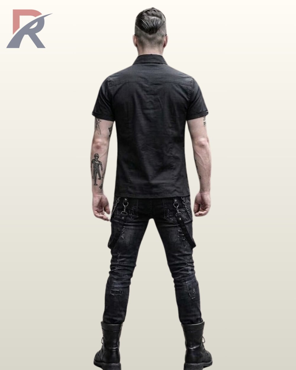 Full rear view of a tattooed male model wearing a black short-sleeve gothic button-down shirt paired with distressed black jeans and combat boots.