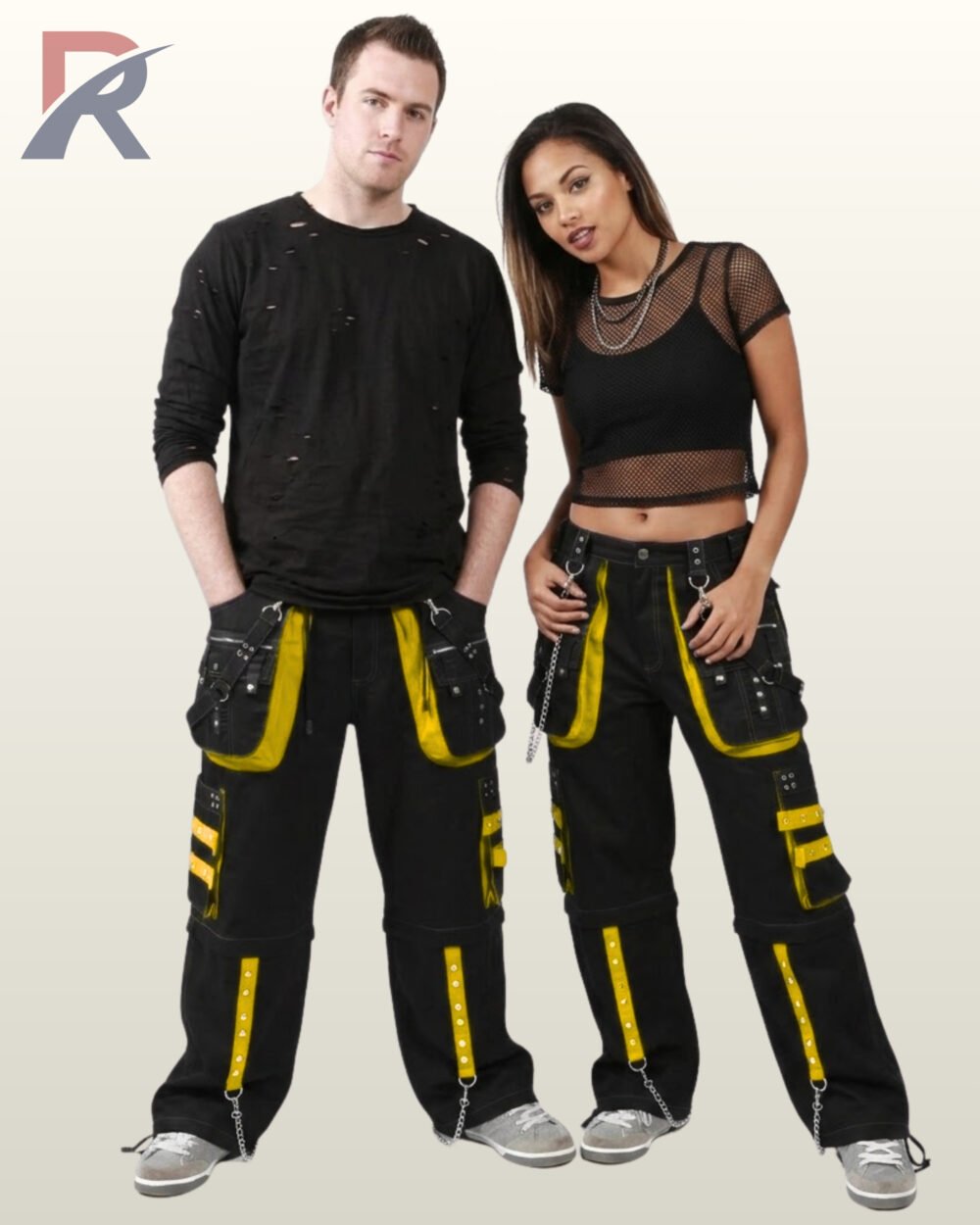 Rear perspective of a man and woman modeling dark cyber goth trousers accented with yellow studded trim and silver hardware.
