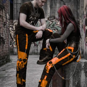 Cyberpunk baggy black bondage trousers featuring orange strap details and metal D-rings.