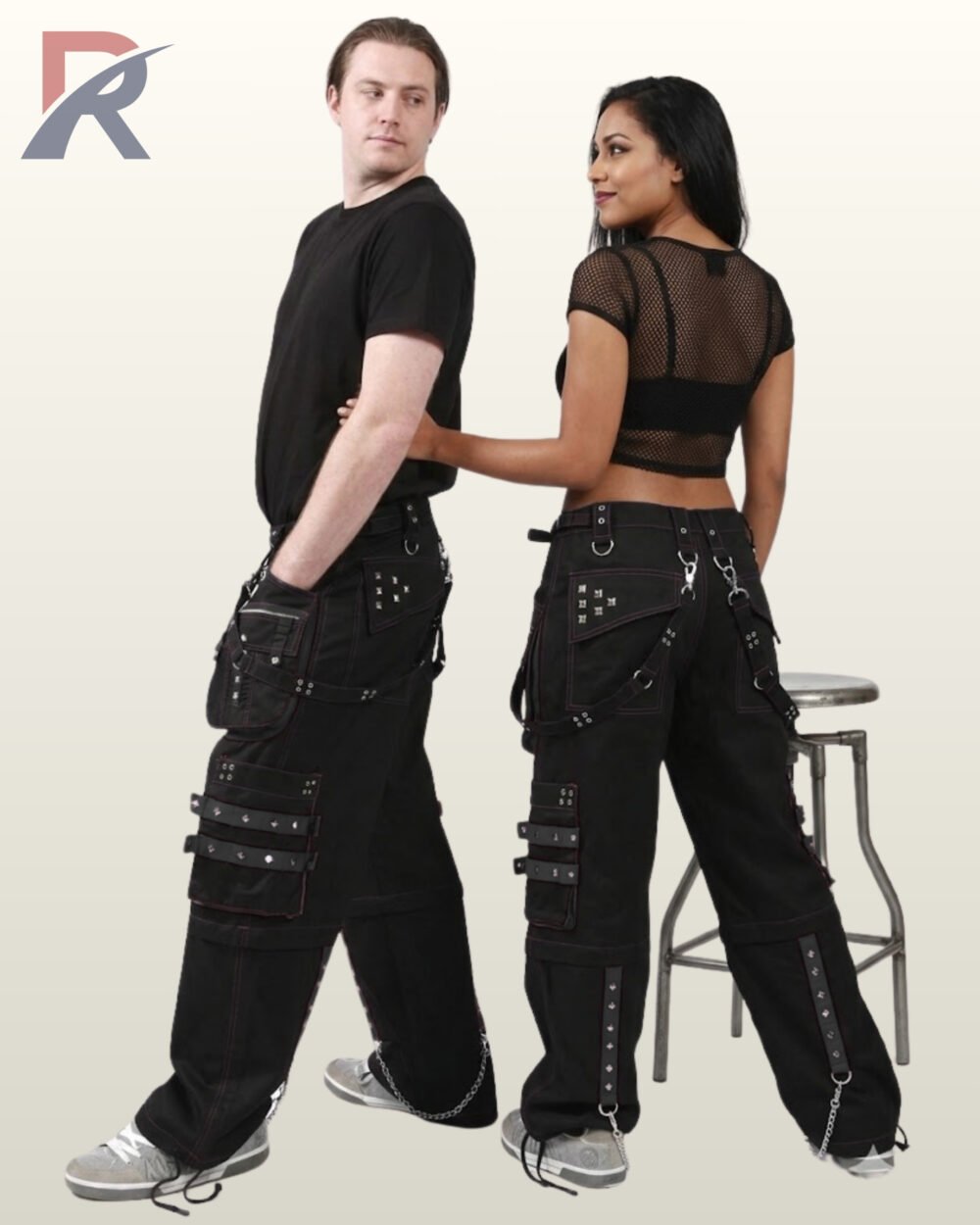 Side and back view of a couple in black gothic cargo pants styled with monochrome black studded straps, utility pockets, and hanging silver chains.