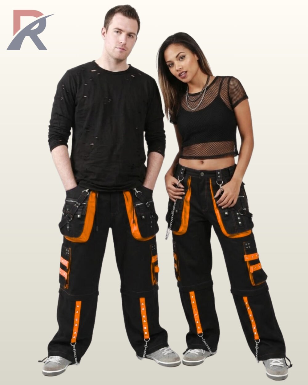 Man and woman modeling wide-leg alternative techwear pants detailed with vibrant orange studded trim and silver chain accents.