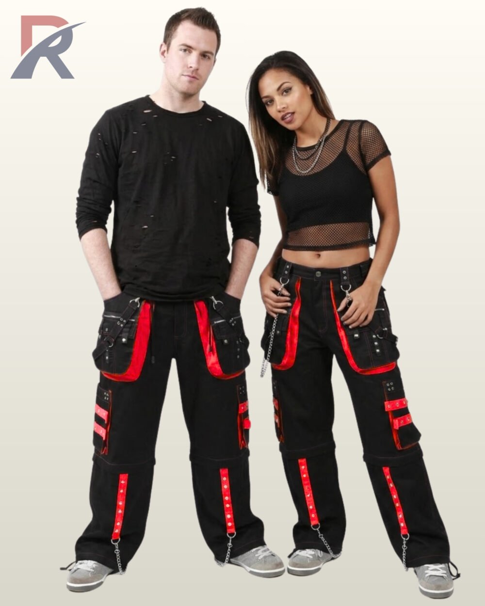 Front view of a man and woman wearing black gothic cargo pants accented with bright red trim, metal studs, and hanging chain hardware.