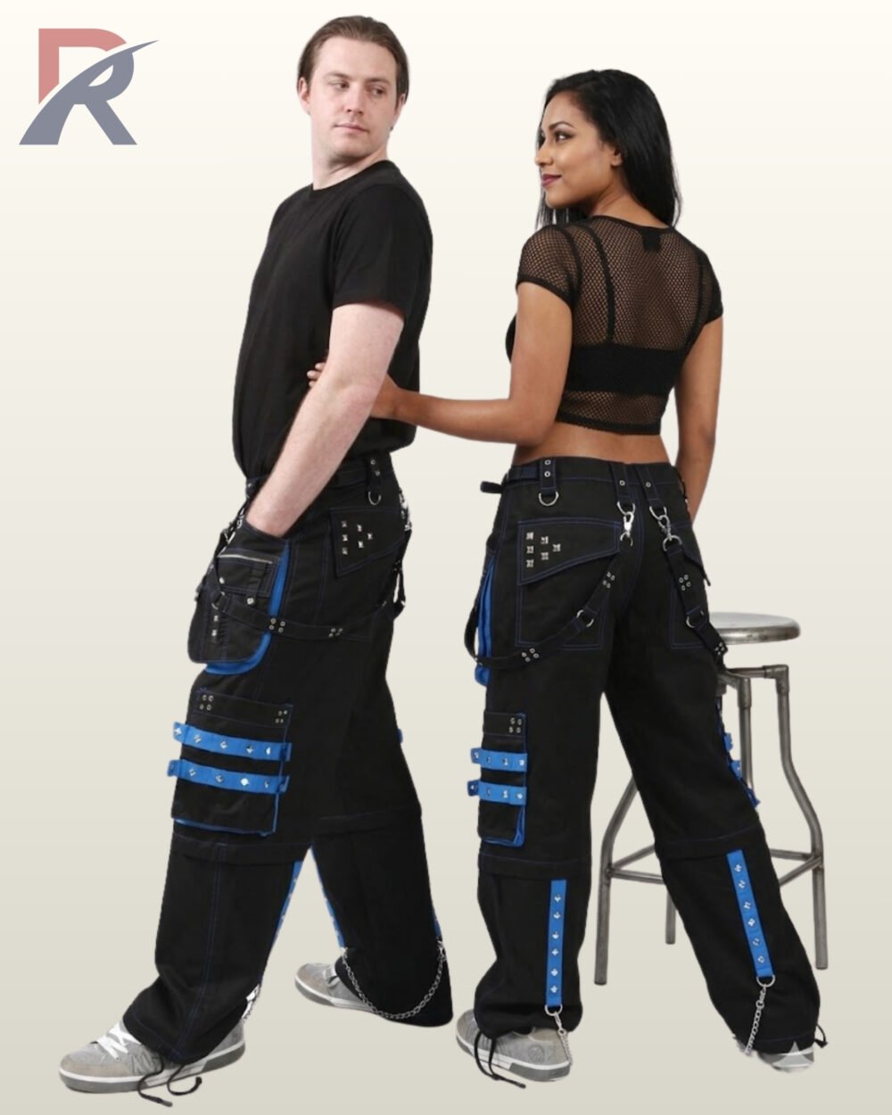 Side and rear view of a couple wearing black gothic wide-leg cargo pants featuring royal blue studded trim, utility pockets, and metal chains.