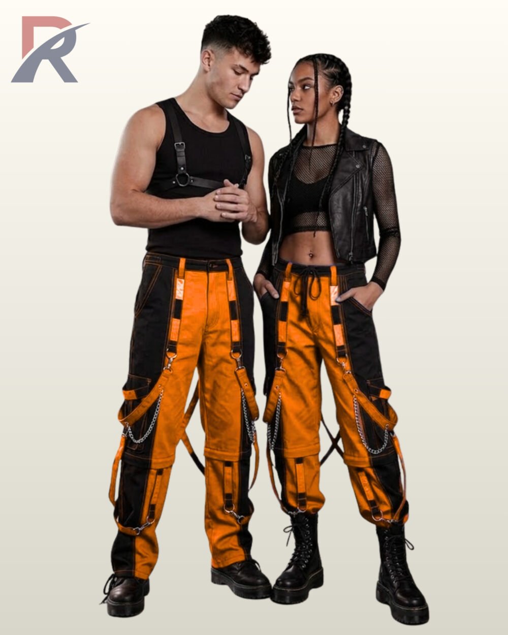 Full model view of a male and female wearing black and pumpkin orange two-tone gothic bondage cargo pants featuring contrast stitching and hanging chains.