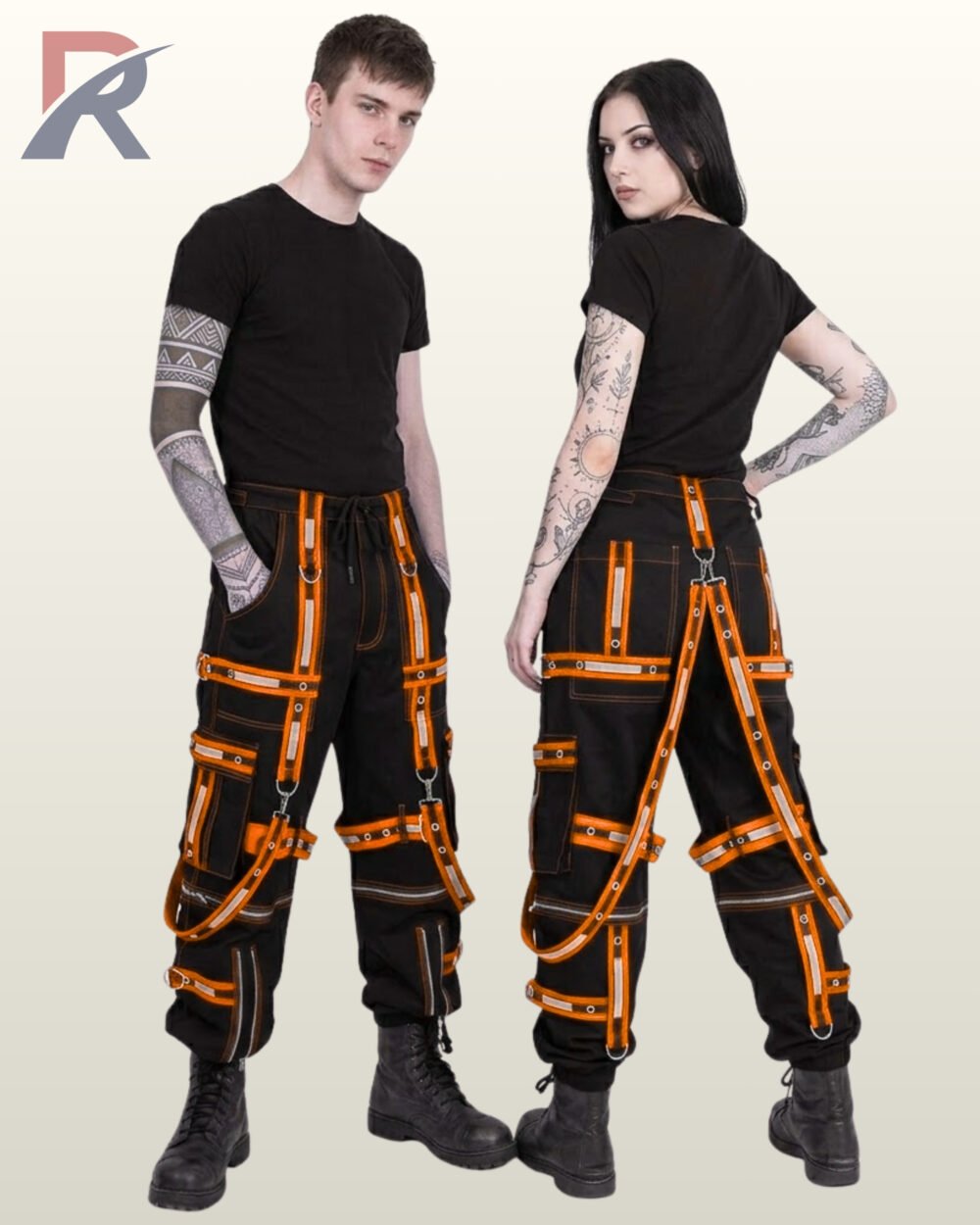 Man and woman modeling alternative cyber goth trousers featuring vivid orange reflective tape and silver metal hardware.