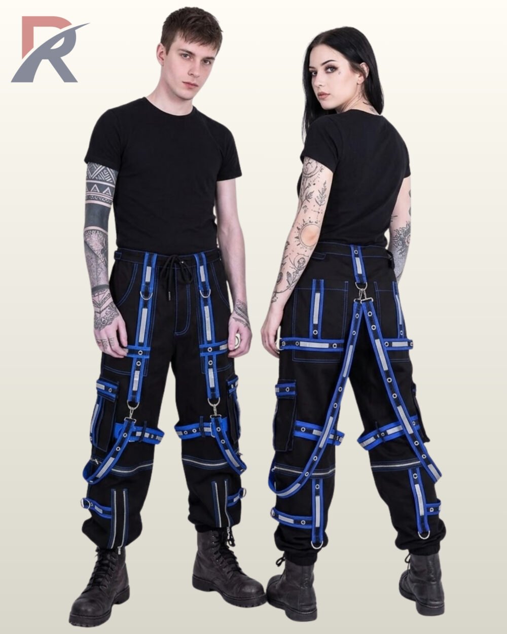 Couple wearing black gothic reflective cargo pants with royal blue eyelet straps, suspender harness details, and utility pockets.