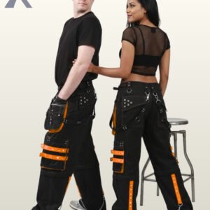 Side and rear view of a couple modeling black gothic cargo trousers with bright orange studded straps, utility pockets, and metal chains.