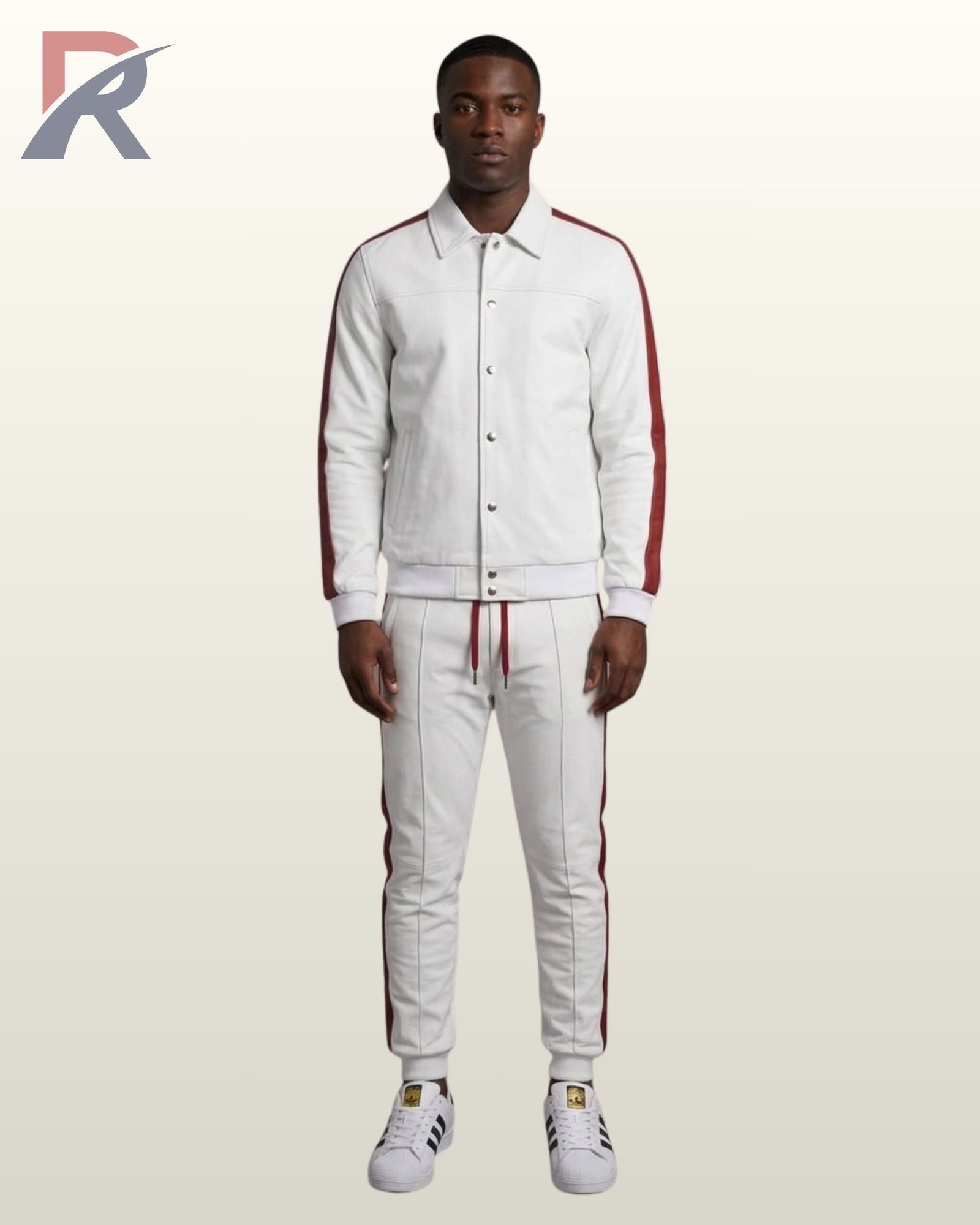 A Black man wearing a premium white streetwear tracksuit featuring a button-up jacket and matching sweatpants with a side maroon stripe.