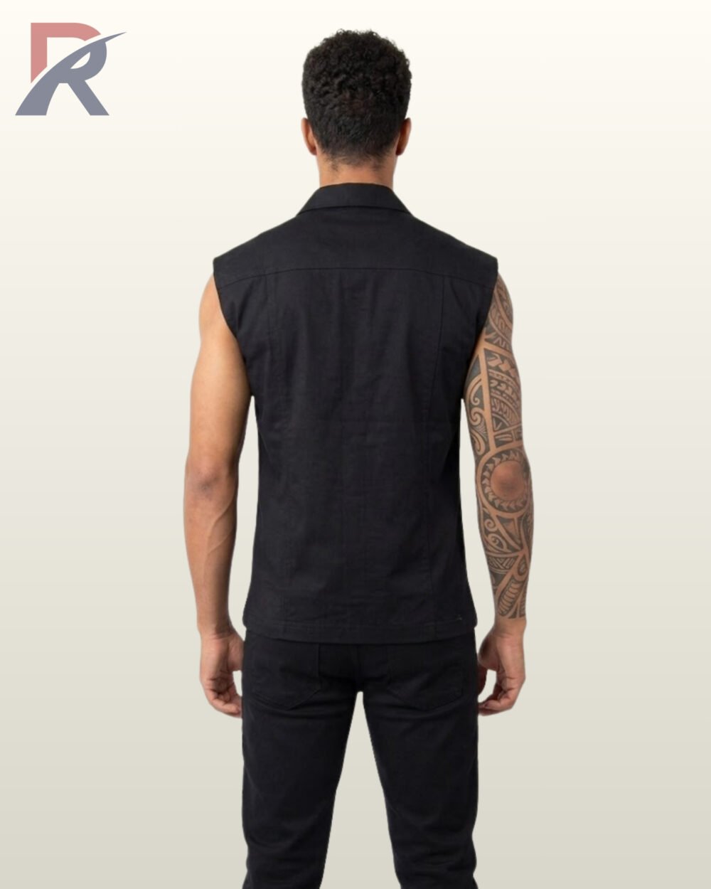 Full rear view of a male model with a tattoo sleeve wearing a black sleeveless gothic biker vest and matching dark trousers.
