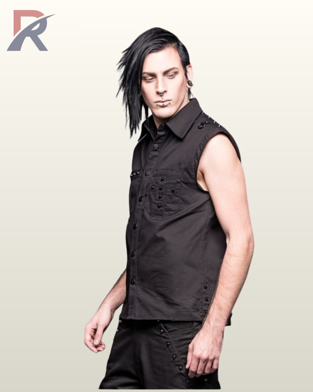 Three-quarter profile view of an alternative male model with facial piercings wearing a black sleeveless gothic button-down shirt with chest studs and shoulder metal rings.