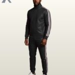 A man standing in a full-body view wearing a premium black leather tracksuit featuring white side stripes.