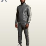A man wearing a charcoal gray leather tracksuit with white sporty side stripes.