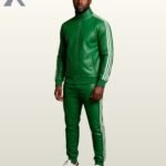 A man standing full-length in a rich emerald green leather tracksuit with crisp white stripes.