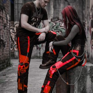 Darkwear loose black bondage trousers featuring red accent straps and hanging metal chain accents.