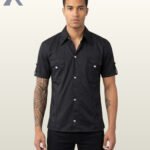 Full front model view of a men's black short sleeve gothic military shirt featuring dual chest flap pockets with silver snap buttons and cuffed sleeve tabs.