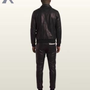 A man wearing a classic black leather tracksuit with white side stripes.