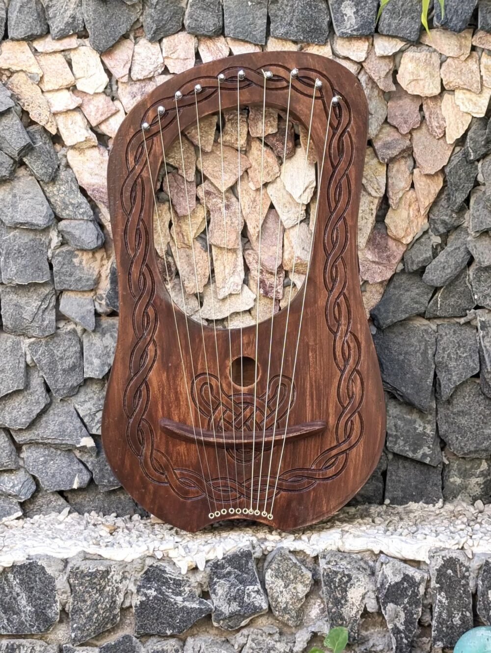 10-string carved wooden lyre harp with dark stain, steel strings, silver tuning pegs, and traditional Celtic relief carvings.