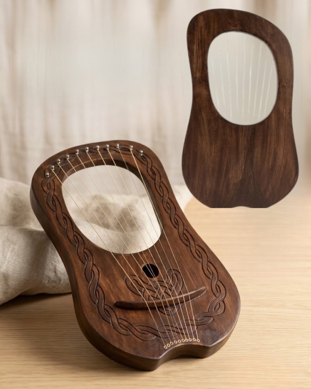 Front view of a 10-string dark rosewood lyre harp resting on a wooden table with hand-carved Celtic braid border, sound hole knotwork, and a rear view inset.