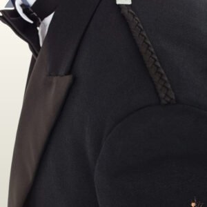 Close-up view of a men's black Prince Charlie kilt jacket shoulder showing black braided epaulet cords and satin lapels.