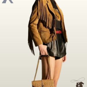 Three-quarter side view of a model wearing a camel tan suede western fringe jacket styled with black shorts and a beige chain handbag.