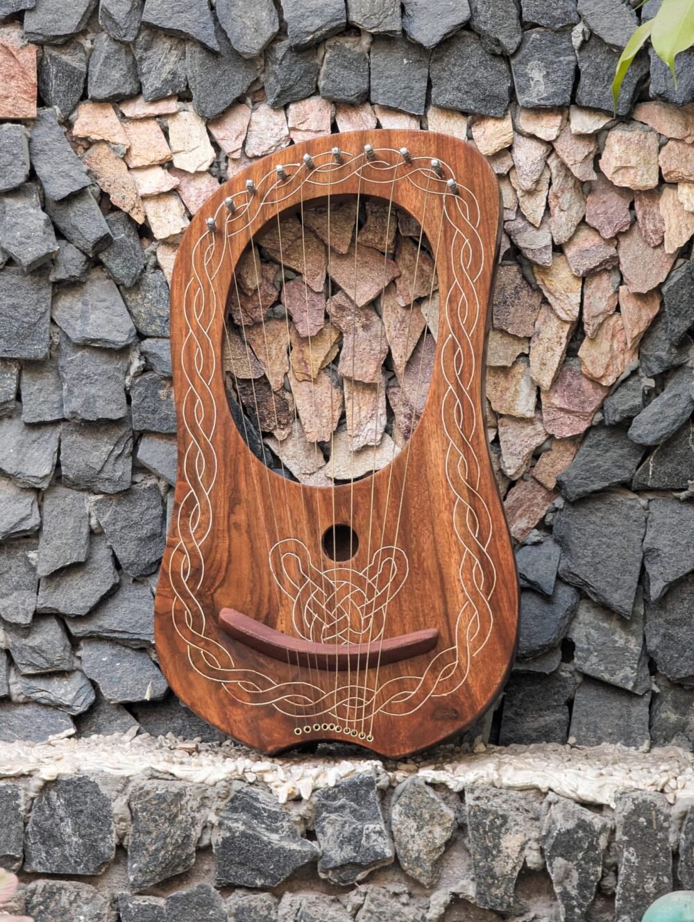 Full front view of a 10-string handcrafted wooden lyre harp featuring white engraved Celtic knotwork border and sound hole design.