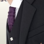Detailed shot of notched lapel tailoring and square silver buttons on a formal men's black wool Argyle kilt jacket.