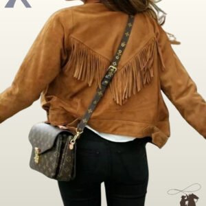 Rear view of a model wearing a women's camel brown suede western jacket featuring a V-shaped fringed back yoke and black pants.