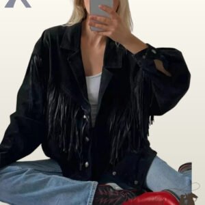 Seated view of a blonde model taking a mirror selfie in a women's black suede western fringe jacket, light blue jeans, and red cowboy boots.