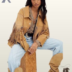 Seated pose of a model wearing an open camel tan suede western fringe jacket styled with slouchy suede boots and light wash jeans.