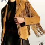 Front close-up view of a model wearing a camel tan suede western fringe jacket featuring tailored notched lapels, chest fringe, and arrow-stitched welt pockets.