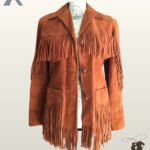 Front view of a women's cognac rust suede western jacket displayed on a mannequin, featuring double-tier chest and pocket fringe with woven button closures.