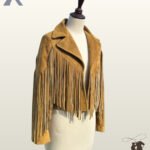 Angled front view of a open mustard tan suede cropped western jacket on a dress form mannequin showcasing wide lapels and chest fringe.