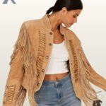 Front view of a model wearing an open tan suede western jacket with bone pipe bead chest panels, silver concho buttons, shoulder fringe, and a white crop top.
