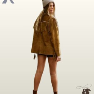Rear full-length view of a model wearing a women's tan suede western fringe jacket with silver studs, paired with a beanie and ankle boots.